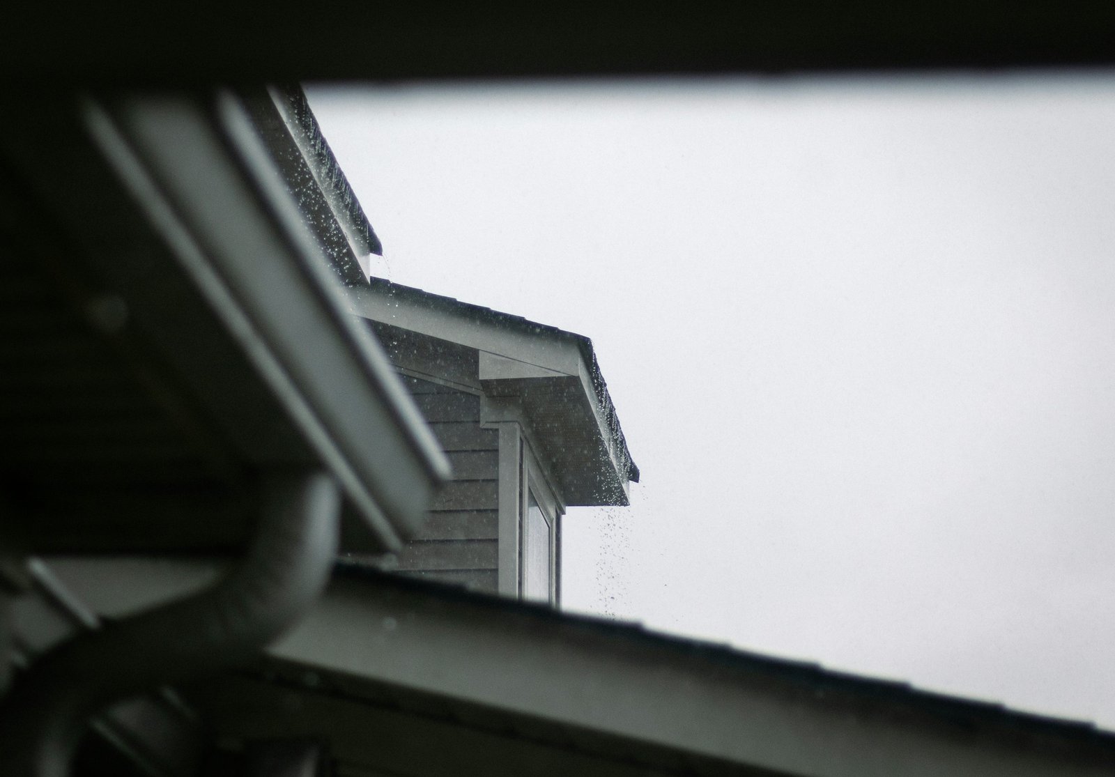 A gutter and downspout at a building roof edge